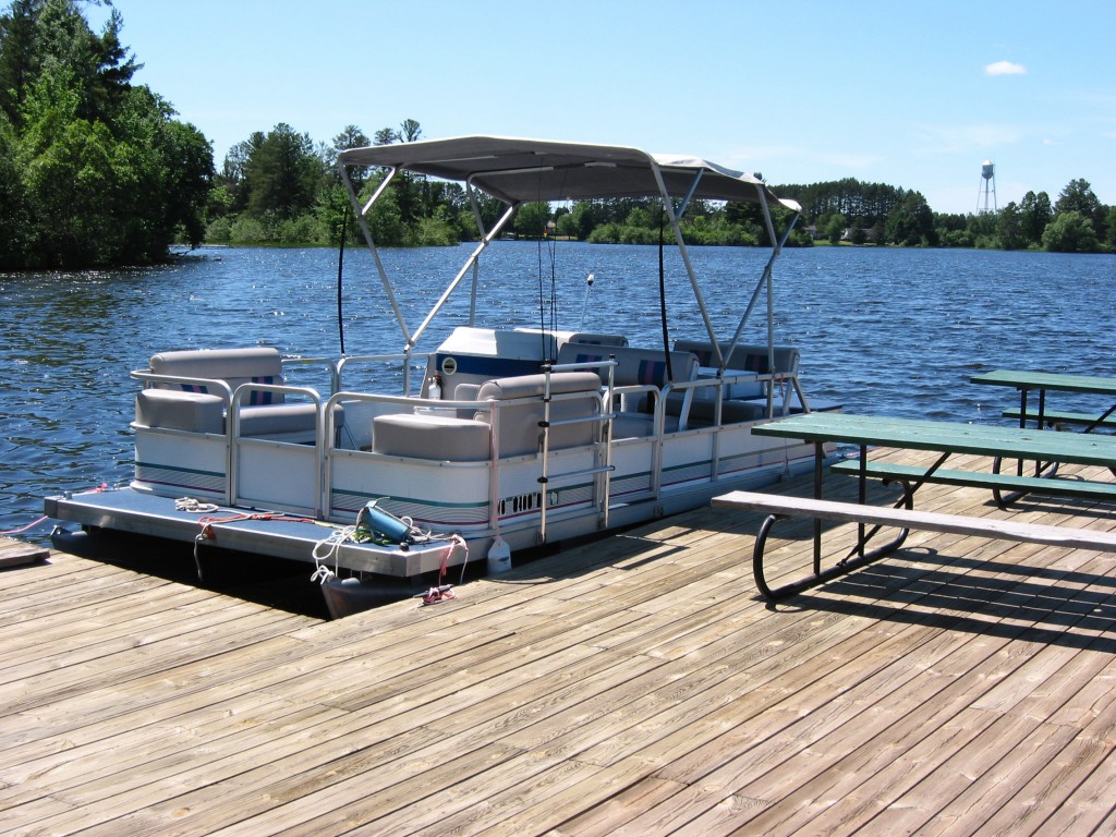 Pontoon party boat docked at the lake, ready for boarding.
