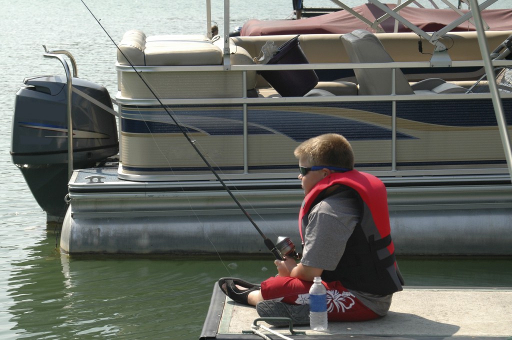 boy fishing near a pontoon boat