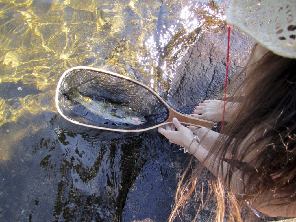Young woman holding a trout in a fishing net